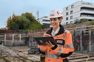 Katarina in einer Baugrube mit Tablet in der Hand am lächeln.