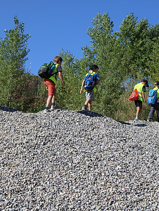 5 Kindern laufen auf einen Kieshaufen um runterzurutschen
