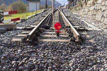 Bahngleis mit rotem Signalschild im Vordergrund, Teil einer Bahninfrastruktur-Anlage.