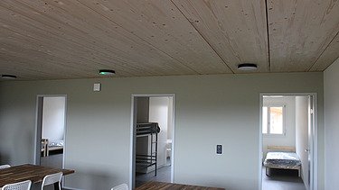 Heller Wohn- und Essbereich mit Holzdecke und Blick in Zimmer.