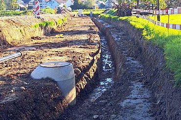 Nachtaufnahme einer STRABAG-Baustelle. Ein grosser Kran steht beleuchtet neben einem Wohnhaus unter dem klaren Nachthimmel.