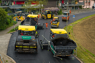 Mehrere Baustellenfahrzeuge und Arbeiter erneuern eine Strassen