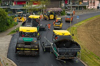 Mehrere Baustellenfahrzeuge und Arbeiter erneuern eine Strassen