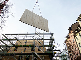 Ein Holzelement in der Luft durch einen Kran wird geliefert für die Dachkonstruktion.