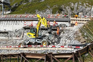 Drohnenaufnahme der Baustelle mit drei Mitarbeitenden wenig unterhalb der Fahrbahn