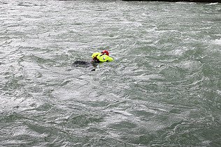 Eine Person schwimmt mit einer automatisch ausgelösten Rettungsweste in der Strömung eines Flusses während einer Wasserrettungsübung.