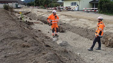 Der Bauführer und Polier sprechen im Flussbett miteinander