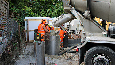 In das Bohrloch, das bereits mit Armierungseisen verstärkt wurde, wird Beton aus einem Betonmischer eingefüllt.