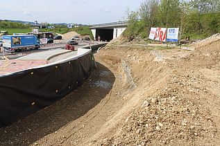 Foto von Graben für Leitungen mit STRABAG Bauzaunbanner im Hintergrund