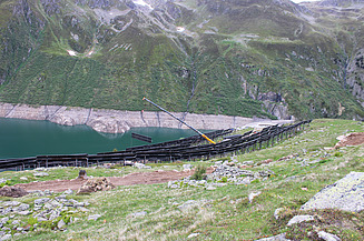 Kran zwischen vielen Solarpanels und im Hintergrund der Stausee Lai da Nalps