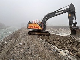 Foto von Arbeiten auf Sandbank der Reuss mit gelben STRABAG Bagger