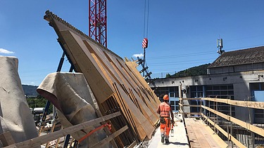  Ein Kran der STRABAG hebt nachts ein langes Brückenteil über Bahngleise. Die Baustelle ist hell erleuchtet.