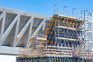 Zwei grosse Hebevorrichtungen auf einer STRABAG-Baustelle. Im Hintergrund sind Bauarbeiter:innen und ein Kran zu sehen.