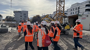 Gruppenbild der Gruppe im Hintergrund ist ein Mini-Bagger und Kran zu sehen