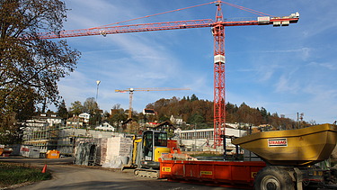 Foto von Rohbau im Vordergund ein Dumper und roter Kran