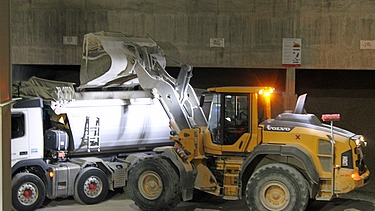 Gelber Bagger verlädt Kies in Lastwagen
