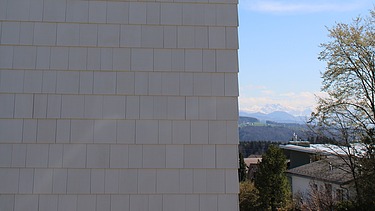 Weisse Schindelfasse mit rechts Aussicht auf die Alpen und die Nachbarschaft