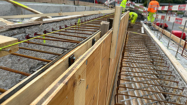 Nachaufnahme der Baustelle mit Schalungselementen und Mitarbeitern im Hinterrgund