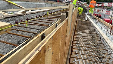 Nachaufnahme der Baustelle mit Schalungselementen und Mitarbeitern im Hinterrgund