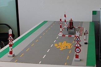 Tischmodell einer Strasse mit Baustellenabsperrungen und Verkehrsschildern zur Schulung der Arbeitssicherheit.