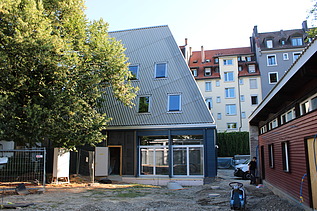 Neues Gmeindezentrum ohne Baugerüst. Das GZ ist in einem Blauton und steht direkt nebem den 2. Gebäude.