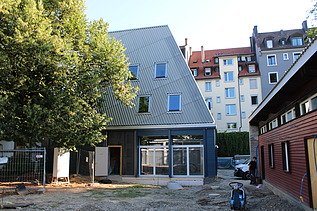 Neues Gmeindezentrum ohne Baugerüst. Das GZ ist in einem Blauton und steht direkt nebem den 2. Gebäude.