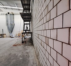 Innenansicht einer Baustelle mit einer grossen Kalksandsteinwand und einer Scherenbühne in einer Logistik Halle.