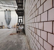 Innenansicht einer Baustelle mit einer grossen Kalksandsteinwand und einer Scherenbühne in einer Logistik Halle.