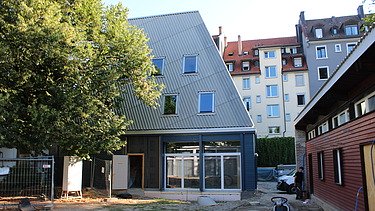 Neues Gmeindezentrum ohne Baugerüst. Das GZ ist in einem Blauton und steht direkt nebem den 2. Gebäude.