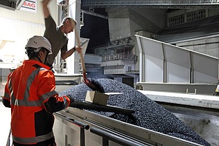 Zwei Männer entnehmen eine Asphaltprobe aus dem geladenen Lastwagen