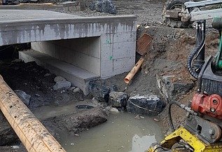 Foto von Durchlassbauwerk mit Rohren und Wasser auf Schlammboden