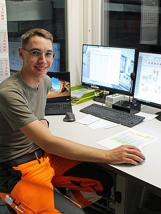 Mann sitzend vor zwei Bildschirmen in der Steuerzentrale