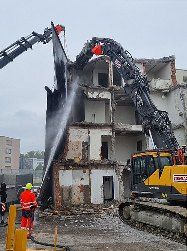 Foto von Bauarbeiter mit Wasserstrahl auf abgebrochenem Gebäude