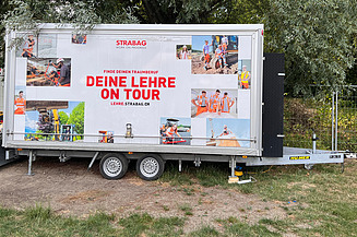 STRABAG Lehrlingsanhänger mit Bäumen im Hintergrund
