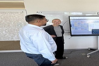 Das Team Innovation & Digitale Transformation bei einem Standup-Meeting vor einem Whiteboard      