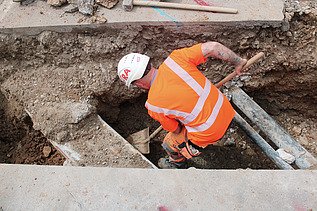 Foto von Arbeiten eines STRABAG Mitarbeitenden im Graben für Werkleitungen in Wangen mit
