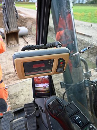 Innenansicht der Baggerkabine mit Blick auf das Steuerpult und das GPS-Display zur digitalen Maschinenführung.