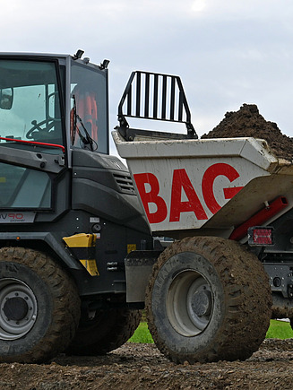 Weisser Kipp­laster der STRABAG auf einer Baustelle, beladen mit Erdmaterial.