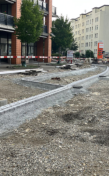 Nachtaufnahme einer STRABAG-Baustelle. Ein grosser Kran steht beleuchtet neben einem Wohnhaus unter dem klaren Nachthimmel.