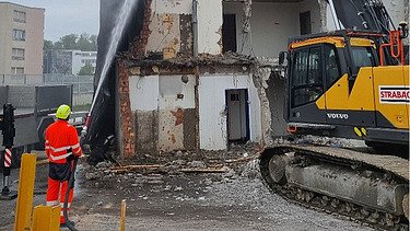 Foto von Bauarbeiter mit Wasserstrahl auf abgebrochenem Gebäude