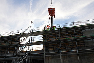 Foto von Rohbau mit Gerüst und Beton vom Kran