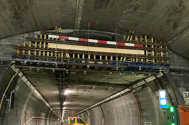 Nachtaufnahme einer STRABAG-Baustelle. Ein grosser Kran steht beleuchtet neben einem Wohnhaus unter dem klaren Nachthimmel.