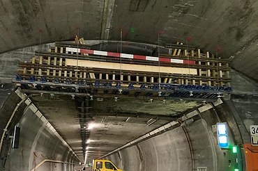 Nachtaufnahme einer STRABAG-Baustelle. Ein grosser Kran steht beleuchtet neben einem Wohnhaus unter dem klaren Nachthimmel.