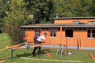 STRABAG Lernender beim zusägen der Latten für die neue Holzfassadenverkleidung des Pfadiheims Hüttikerberg