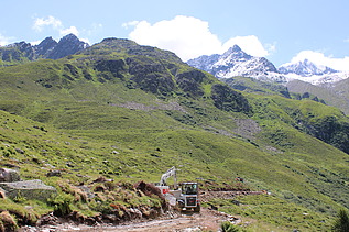 Weisse STRABAG Baumaschinen, im Hintergrund Berglandschaft