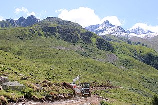 Weisse STRABAG Baumaschinen, im Hintergrund Berglandschaft