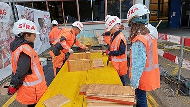 Mädchen mit Baustellenkleidung auf der Baustelle bekommen Arbeit erklärt