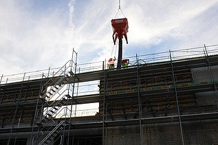 Foto von Rohbau mit Gerüst und Beton vom Kran