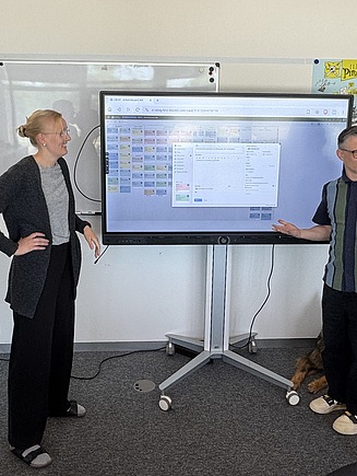 Das Team Innovation & Digitale Transformation bei einem Standup-Meeting vor einem Whitebordt      
