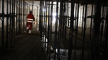 Arbeiten in der Baustelle, dunkel, ein Bauarbeiter von hinten